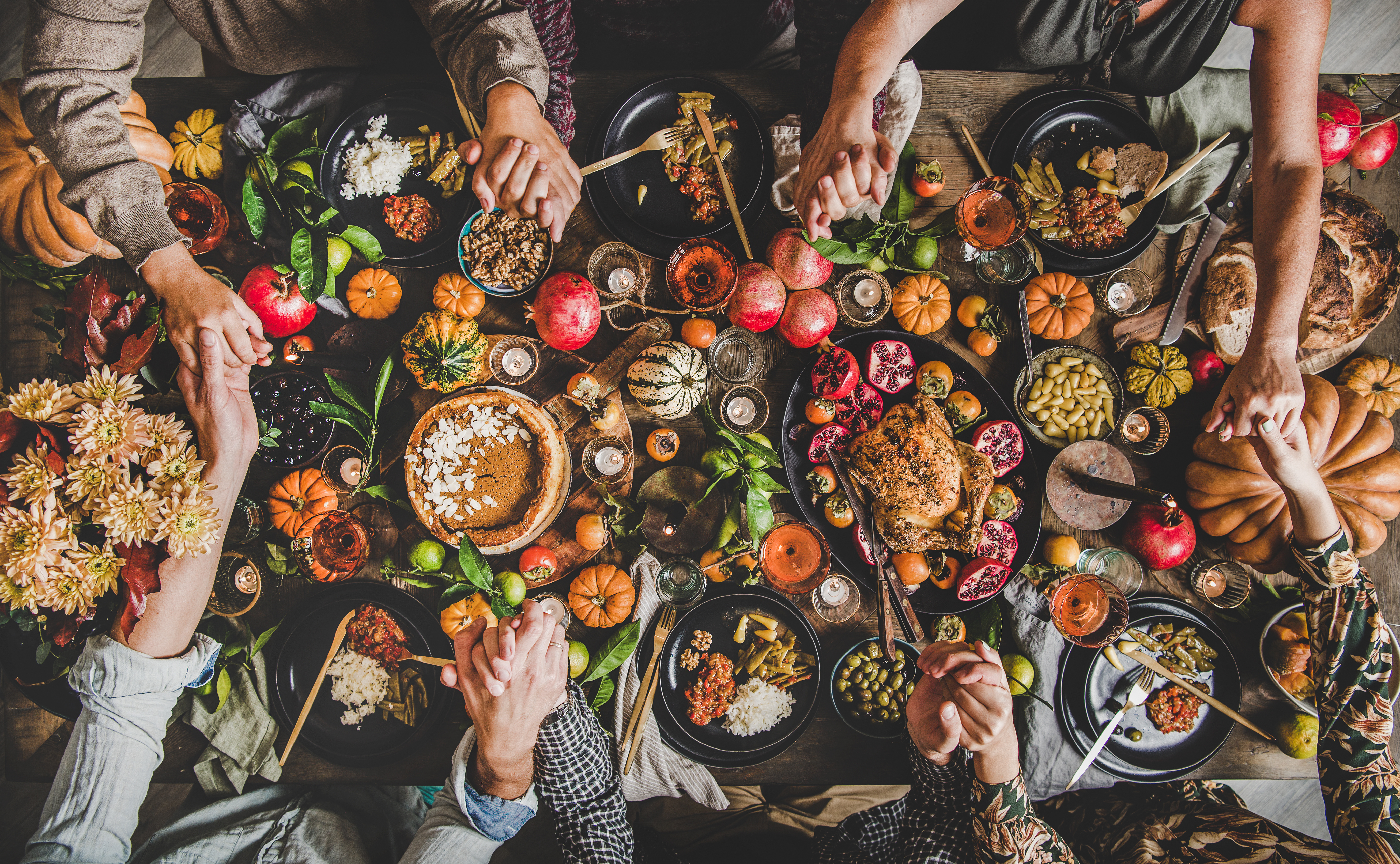 thanksgiving table filled with food and hands grabbing food